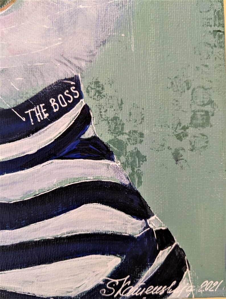 May include: A close-up of a painting of a person wearing a striped shirt with the text "THE BOSS" on it. The background is a light green color.