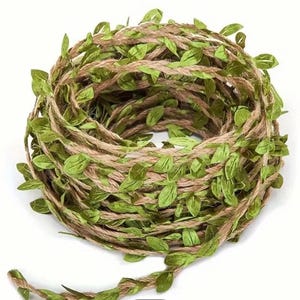 May include: A coiled garland made of jute twine, decorated with small, bright green leaves. The natural brown twine provides a rustic base for the artificial foliage. Suitable for craft projects and home decoration.