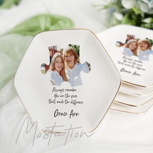 May include: Set of white hexagonal ceramic plates with gold trim. Each plate features a photo of two people in a puzzle piece shape and the text "Always remember... You are the piece that made the difference. Grace Ann."