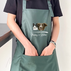 Peut inclure: Tablier vert avec une grande poche, représentant un chat blanc et un chien brun avec le texte "Mummy's Kitchen" imprimé sur le devant.