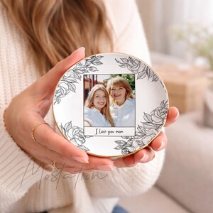May include: A white ceramic plate with a gold rim, featuring a photo of two women and the text "I love you mom." The plate is decorated with black floral designs.