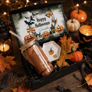 Pu&ograve; includere: Una scatola regalo nera contenente un bicchiere di vetro con coperchio in bamb&ugrave; e cannuccia, un piccolo piattino esagonale bianco con illustrazione di zucca e una collana color oro. Il coperchio presenta una grafica Happy Halloween.