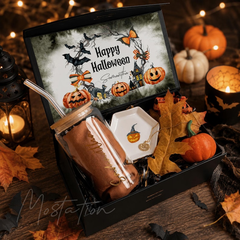 Pu&ograve; includere: Una scatola regalo nera contenente un bicchiere di vetro con coperchio in bamb&ugrave; e cannuccia, un piccolo piattino esagonale bianco con illustrazione di zucca e una collana color oro. Il coperchio presenta una grafica Happy Halloween.