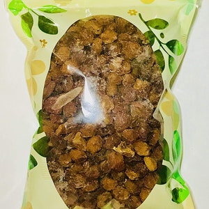 May include: A clear plastic bag with a yellow and green floral design. The bag contains a large amount of dried brown raisins.