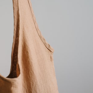 May include: A light brown linen tote bag with a wide opening and two long straps.