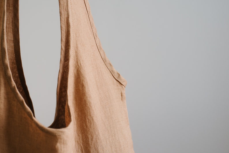 May include: A light brown linen tote bag with a wide opening and two long straps.