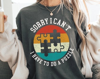 May include: A gray sweatshirt with a vintage-style graphic of a puzzle piece and the text "Sorry I can't I have to do a puzzle".