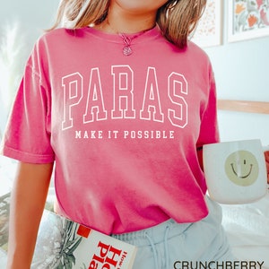 May include: A pink t-shirt with white text that reads "Paras Make It Possible".