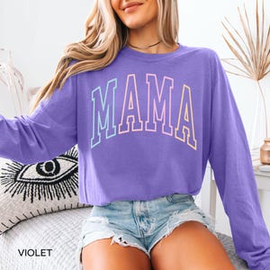 May include: A purple long-sleeved t-shirt with the word "MAMA" in a rainbow arch design.