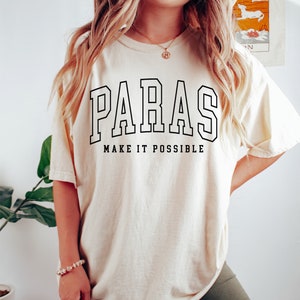 May include: A cream coloured t-shirt with black text that reads "PARAS MAKE IT POSSIBLE".