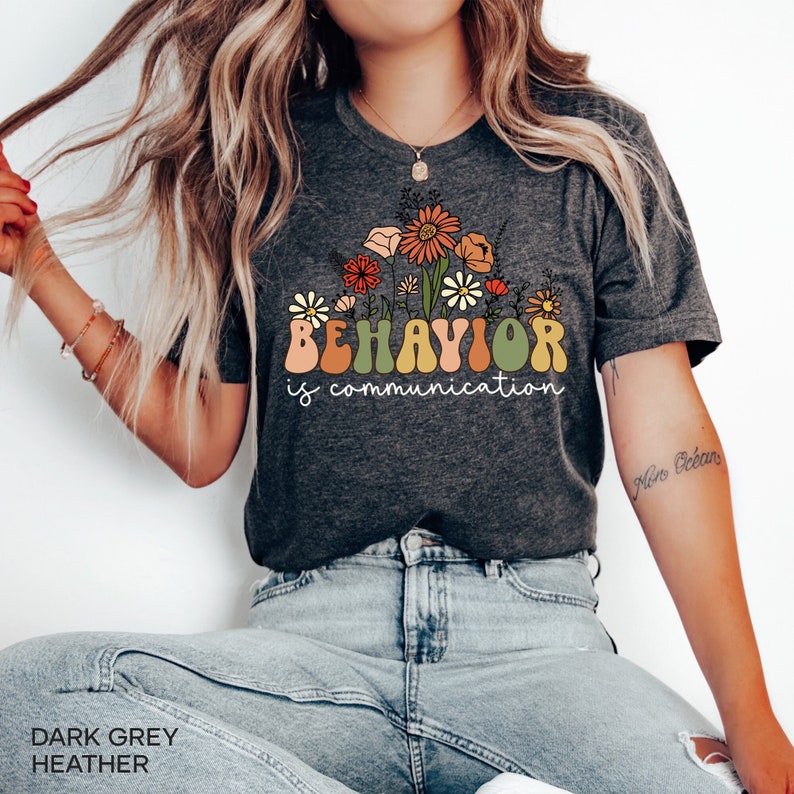 May include: Dark grey heather t-shirt with a floral design and the text "BEHAVIOR is communication".