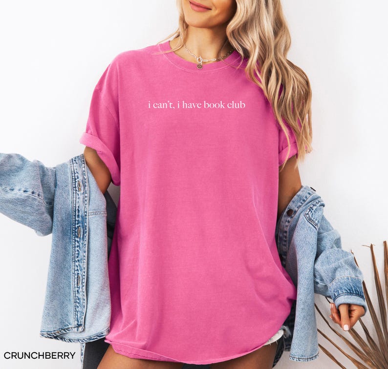 May include: A pink t-shirt with the text "i can't, i have book club" printed in white on the front.