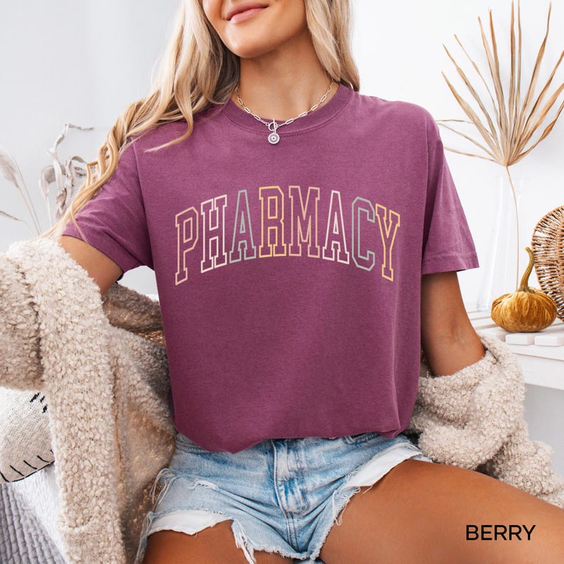 May include: A mauve t-shirt with the word "PHARMACY" printed in a rainbow arch design.