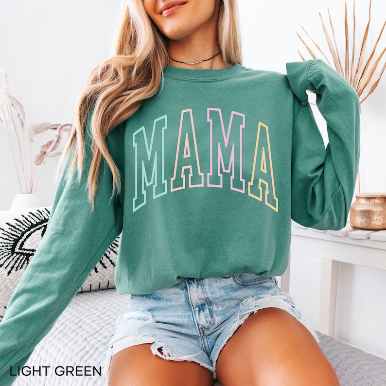 May include: A light green long-sleeved sweatshirt with the word "MAMA" printed in rainbow colors across the front.