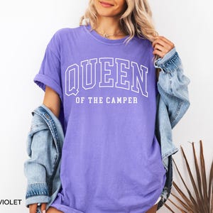 May include: A purple t-shirt with the text "QUEEN OF THE CAMPER" in white.