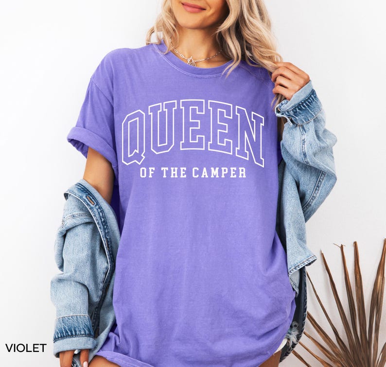May include: A purple t-shirt with the text "QUEEN OF THE CAMPER" in white.