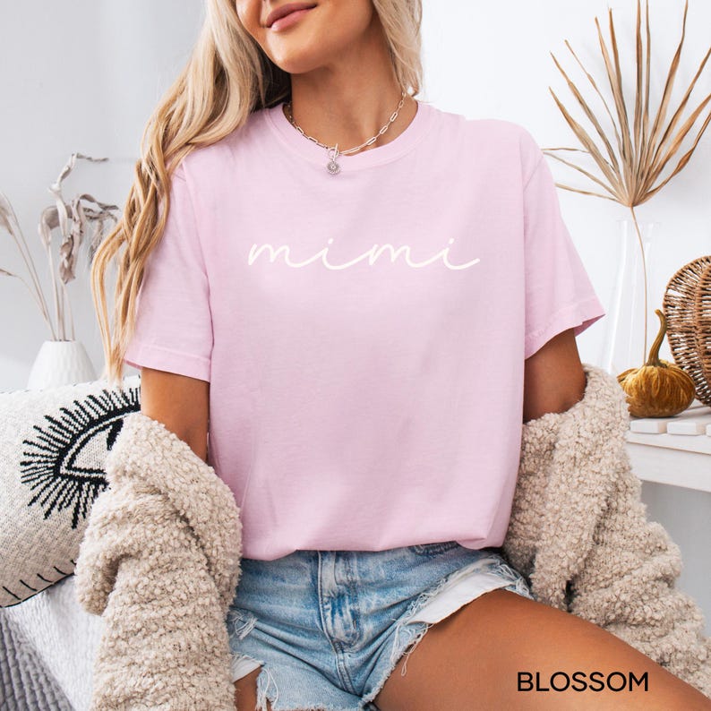 May include: A pink t-shirt with the word "mimi" written in white cursive script.