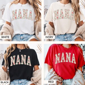 May include: Four t-shirts in white, ivory, black, and red. Each shirt features the word "NANA" in a floral design. The shirts are short-sleeved and have a casual, relaxed fit. The word "WHITE", "IVORY", "BLACK", and "RED" are printed below each shirt.