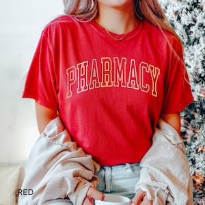 May include: Red t-shirt with the word "PHARMACY" in white outlined letters.
