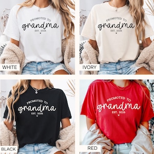 May include: Four t-shirts in white, ivory, black, and red, each with the text "PROMOTED TO grandma EST. 2026" in a cursive font. The shirts are displayed on a person.