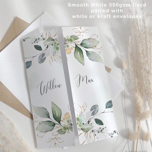 May include: Two white cards with floral designs and the names "Willow" and "Max" in elegant script. The cards are adorned with green leaves and gold accents. The text at the top reads "Smooth White 350gsm Card paired with white or kraft envelopes."