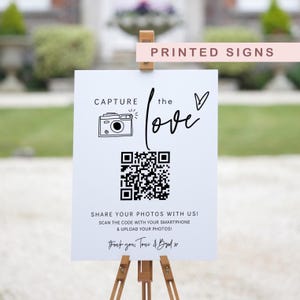 May include: White sign with black text and a QR code. The text reads "Capture the love" and "Share your photos with us! Scan the code with your smartphone & upload your photos! Thank you, Toni & Brad x".