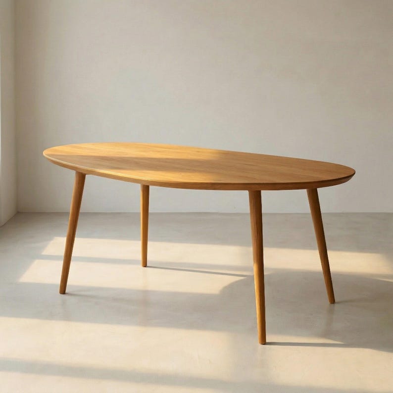 May include: A light brown, oval-shaped wooden table with four tapered legs. The table has a smooth surface and a natural wood grain finish. The legs are evenly spaced and angled slightly outward, providing stability. The table is a piece of furniture.