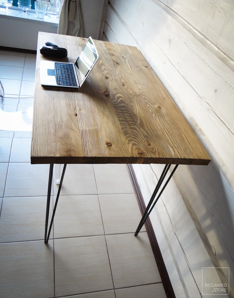May include: A wooden desk with a natural finish and black hairpin legs. A laptop computer is on the desk.