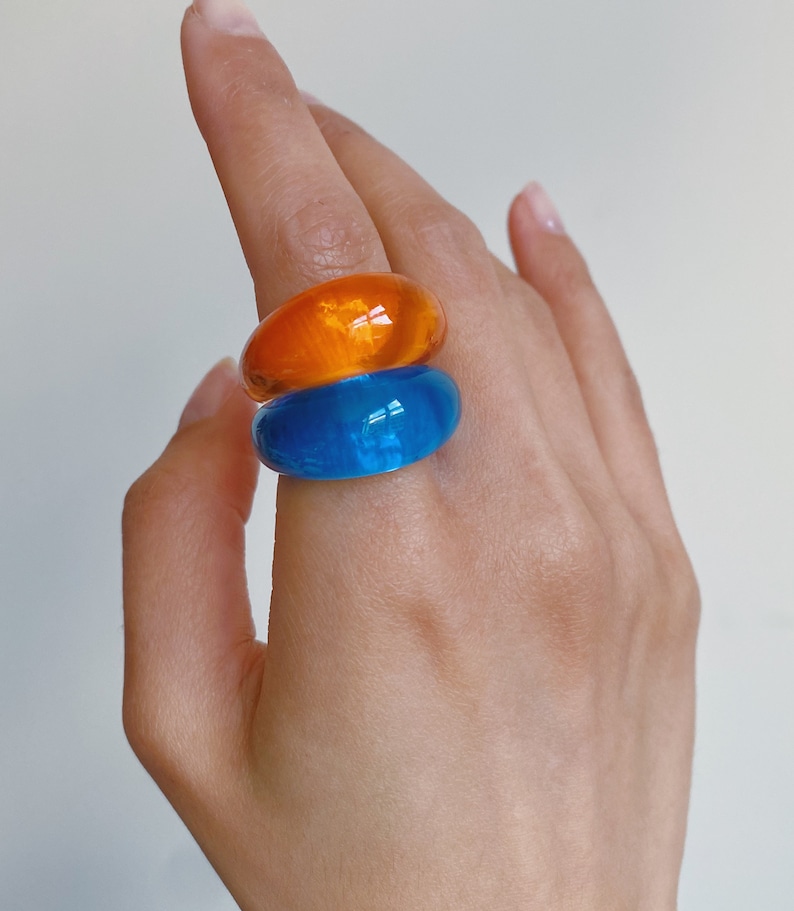 hand wearing two chunky 90s bubble rings in orange and blue