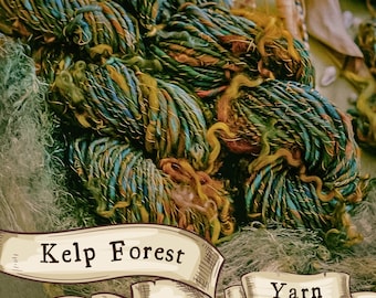 Pode incluir: Um close-up de um novelo de fio em tons de azul-turquesa, verde e marrom. O fio é rotulado como "Kelp Forest Yarn".