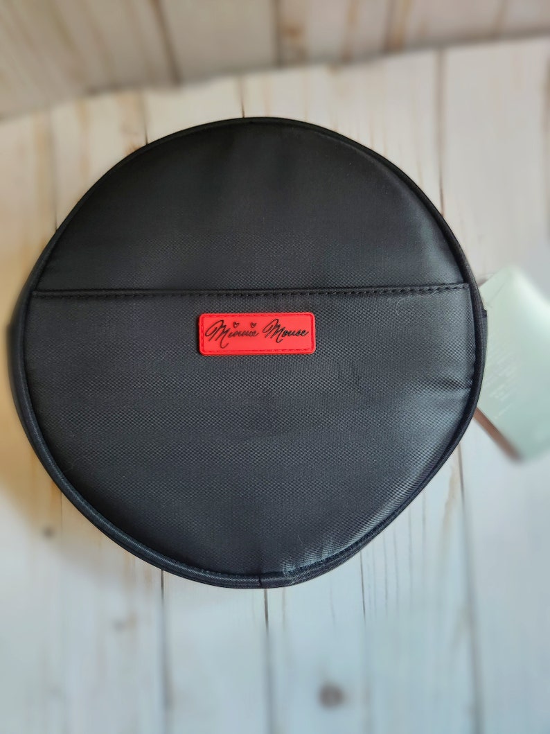 May include: A black round zippered pouch with a red label that says "Minnie Mouse" in white lettering.