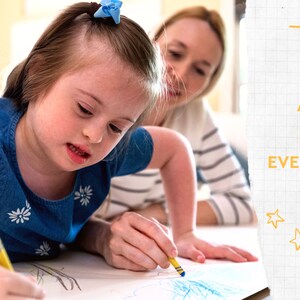 May include: A young girl in a blue denim dress with white floral accents is drawing with a yellow crayon. An adult is assisting. The image includes the text "ART IS FOR EVERYONE!" with yellow stars and lines.