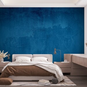 May include: A bedroom with a bed, nightstands, and a blue textured wall. The bed has a brown blanket and white pillows. The nightstands are made of wood and have lamps on them.