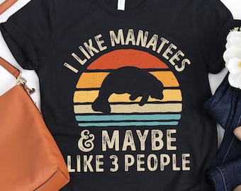 May include: Black t-shirt featuring a vintage sunset graphic and the text "I like manatees & maybe like 3 people".