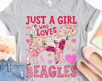 May include: A heather gray t-shirt with the text "JUST A GIRL WHO LOVES BEAGLES". The shirt features a floral beagle design with pink and red flowers, hearts, and text. The shirt is paired with denim shorts and pink flats.