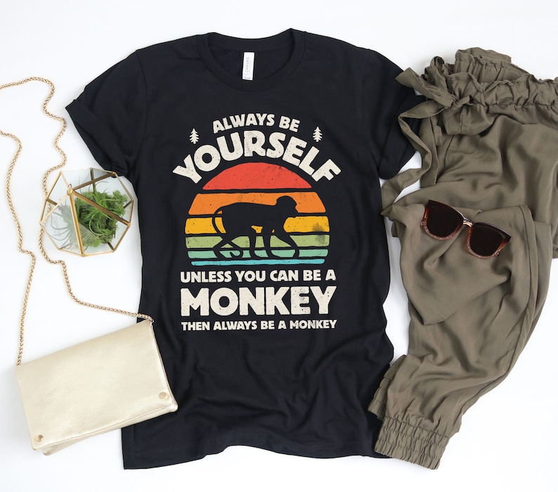 May include: Black t-shirt with a retro sunset graphic and a monkey silhouette. The text reads "Always be yourself unless you can be a monkey then always be a monkey."
