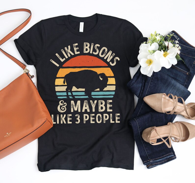 May include: Black t-shirt with a vintage-style sunset graphic and the text "I like bisons & maybe like 3 people".