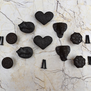 May include: A set of 10 black cast iron drawer pulls with various designs, including hearts, elephants, and hedgehogs. The pulls come with screws for installation.