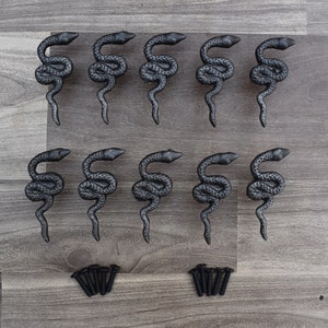 Puede incluir: Doce pomos de armario de metal negro en forma de serpiente con acabado texturizado y doce tornillos negros.