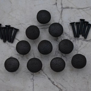 Può includere: Dieci pomelli per mobili in metallo nero con finitura martellata e un set di viti.