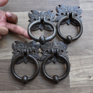 Peut inclure: Quatre heurtoirs de porte en métal noir de style antique avec des motifs floraux ornés. Chaque heurtoir a un anneau circulaire et un bouton arrondi.