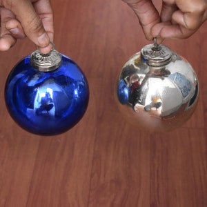 May include: Two Christmas baubles, one blue and one silver, with a reflective surface.