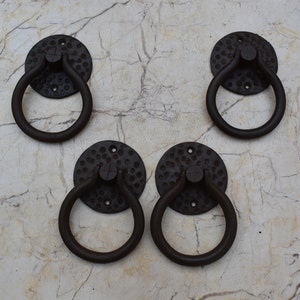 May include: Four black metal ring door pulls with a hammered finish. Each pull has a round base with a ring handle.