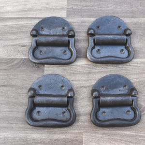 Puede incluir: Cuatro tiradores de cajón de metal negro con forma rectangular redondeada y un asa elevada. Los tiradores tienen un acabado desgastado y están diseñados para su uso en armarios, cajones o muebles.