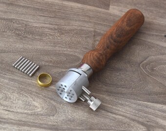 May include: A silver ring mandrel with a wooden handle. The mandrel has a series of holes for sizing rings. There are also several small metal rods and a brass ring included.