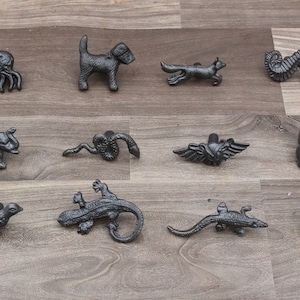 May include: A set of 12 black cast iron animal drawer pulls. The pulls feature a variety of animals, including a dog, fox, seahorse, rabbit, elephant, snake, lizard, and squirrel.