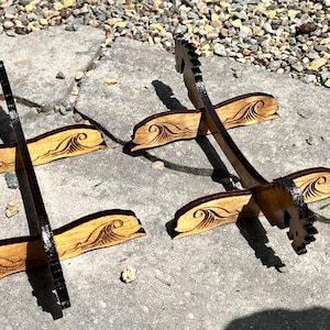 Puede incluir: Expositores de madera con dise&ntilde;o de olas. Los expositores est&aacute;n hechos de madera de color claro con un borde y un patr&oacute;n de olas marr&oacute;n oscuro. Los expositores est&aacute;n dise&ntilde;ados para sostener objetos y se exhiben al aire libre.