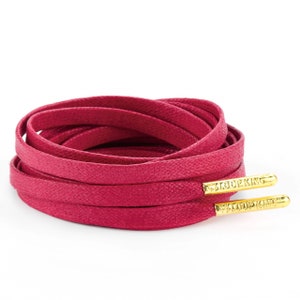 May include: A pair of pink shoelaces with gold aglets that say "Loop King".