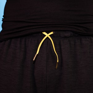 May include: Black pants with a yellow drawstring.