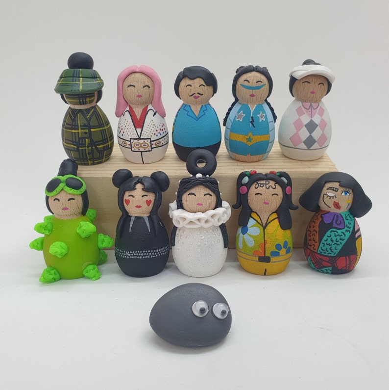 May include: A collection of 11 hand-painted figurines, including a rock, with various designs and colors. The figurines are made of polymer clay and have a whimsical, folk art style.